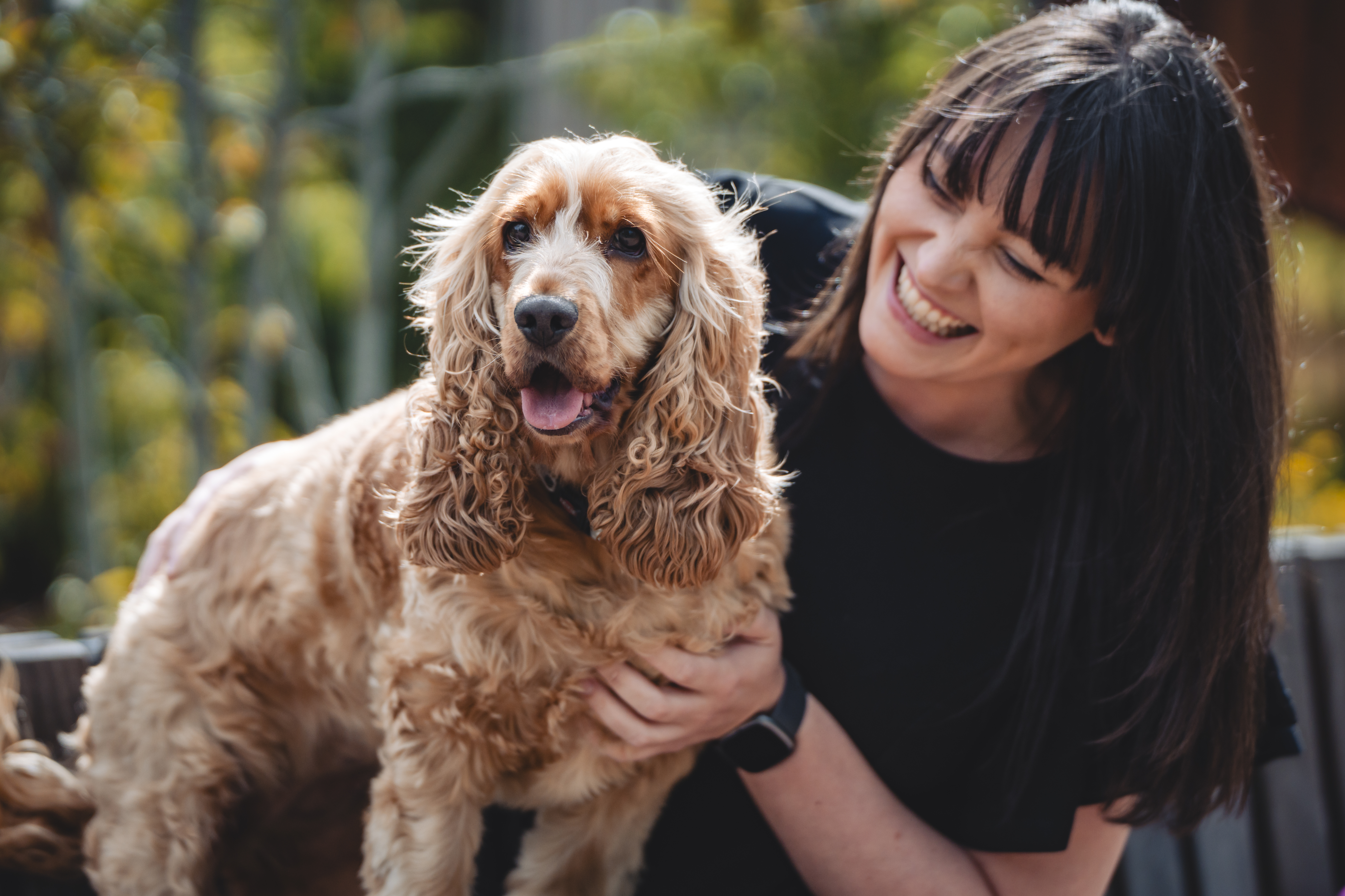 Femme souriante tenant un chien épagneul heureux à l'extérieur.