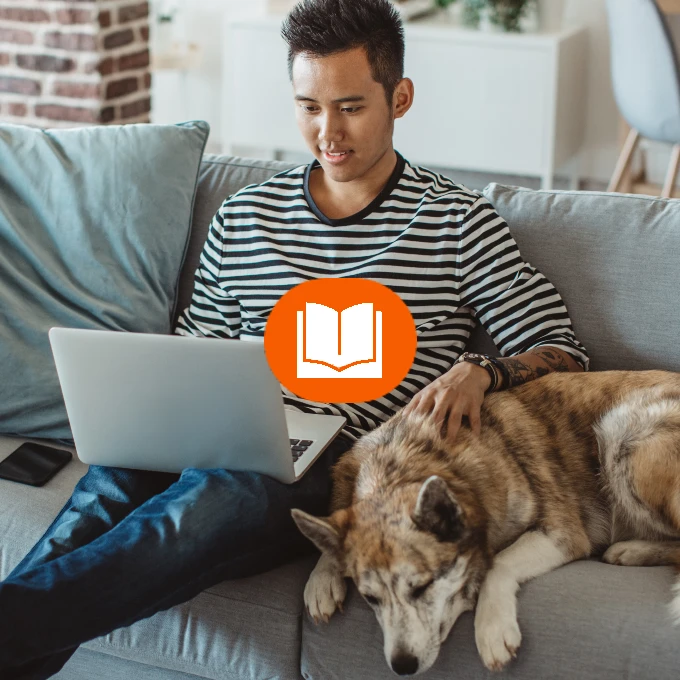 Jeune homme travaillant sur un ordinateur portable, avec un chien allongé à côté de lui sur un canapé, et une icône de livre orange superposée.